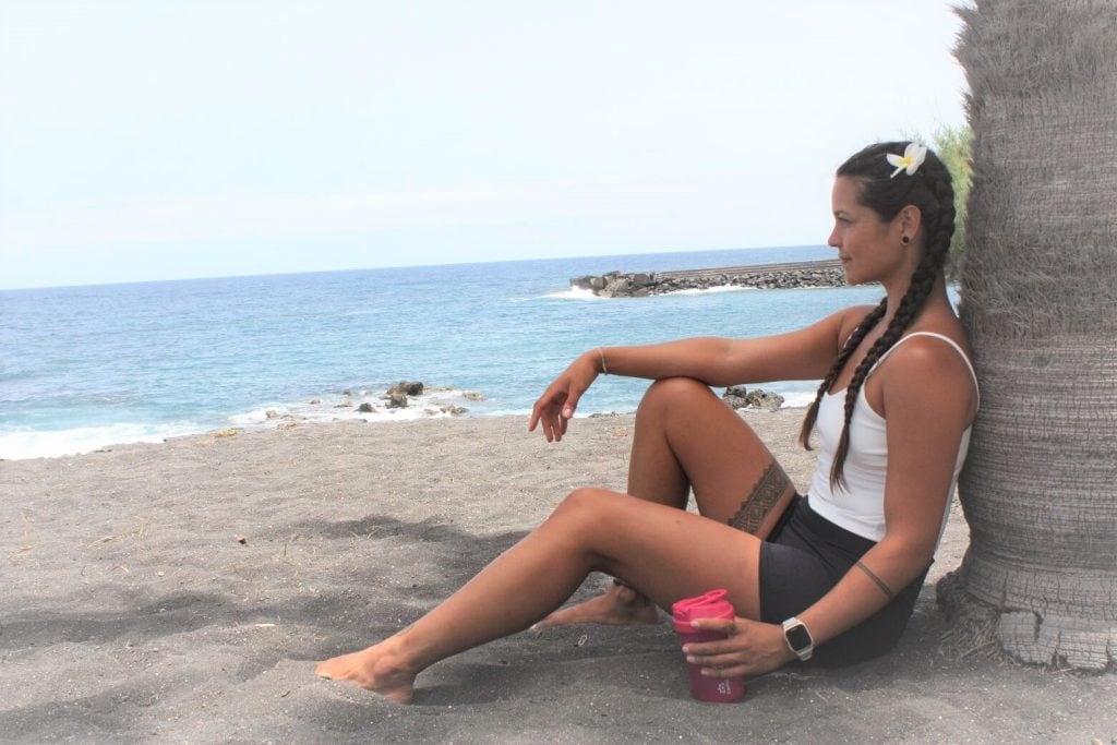 Stefanie Grace sitting on the beach and gazing at the ocean.